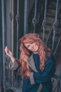 Kızıl saçlı, güzel ve çekici bir kadın zarif bir ceketle güler ve güler sonbaharda.