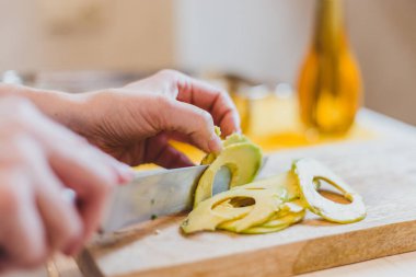 Kadın öğle yemeği hazırlıyor, ızgara ekmek sandviçi yapıyor ahşap kesim tahtasında bruschetta servis ediyor, yeşil salata, krem peynir, avokado - sağlıklı yiyecek.
