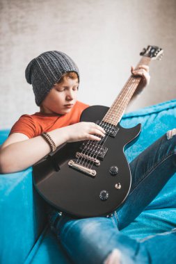 Kızıl saçlı çocuk evde gitar çalıyor. Rock yıldızı. 