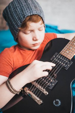 Yakından gelen çocuk özenle ve özenle gitar çalıyordu - müzik eğitimi.