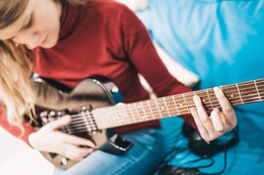 Sarışın, uzun saçlı bir kız siyah bir elektro gitarla hard rock çalıyor.