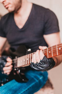 Siyah tişörtlü ve kot pantolonlu bir rockçı siyah bir elektro gitarda hard rock çalıyor.