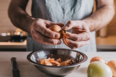 Profesyonel aşçı elleri büyük beyaz soğanların kabuklarını söker.