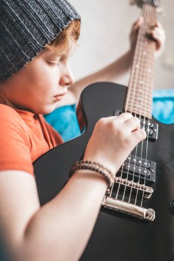 Yakından gelen çocuk özenle ve özenle gitar çalıyordu - müzik eğitimi.