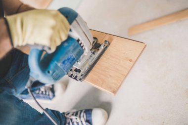 Usta elektrikli bir yapbozla plastik bir tahta kesiyor. Tamirci.