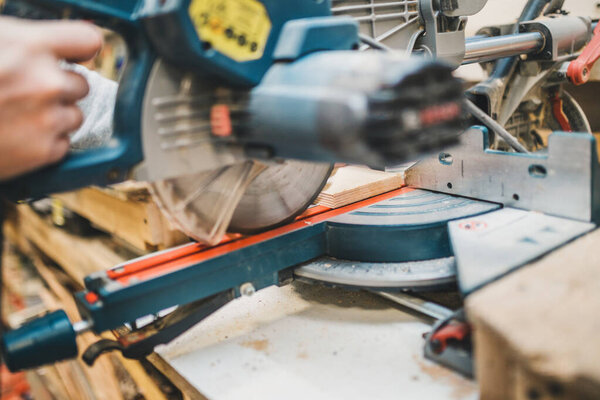 Carpentry workshop - close up work on trimmer - sawing a wooden bar