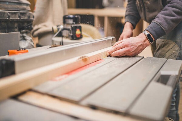 Carpentry workshop - carpenter works on a circular machine - cut bar