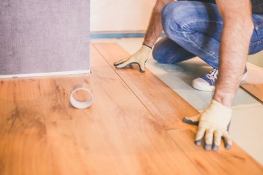 Müteahhit odaya lamine döşemekle meşgul. Tamir ve bitirme işi.