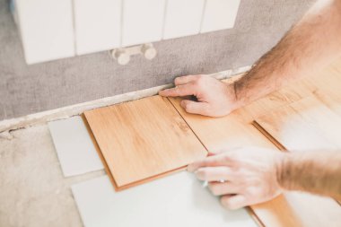 Avrupalı adam evde çalışıyor - döşeme teknolojisi - duvarın yakınındaki kaplamaları kesiyor