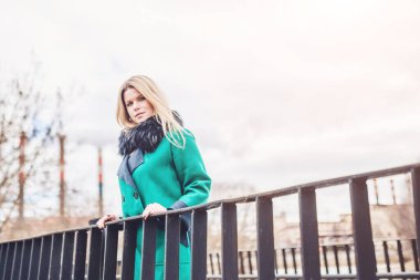 Güzel bir kızın portresi. Köprüde kalın sarı saçlı. İlkbaharda yürürken.