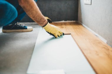 Yeni kaplamalı ahşap zemin döşemesi takan adam.