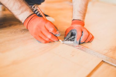 Yeni kaplamalı ahşap zemin döşemesi takan adam.