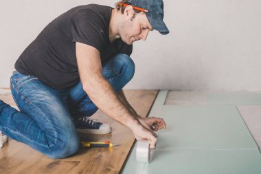 Evde çalışan Avrupalı bir adam - laminat döşemek için polistiren döşeme