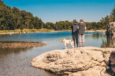 Vers-Pont-du-Gard, Gard / Occitanie / France - 26 Eylül 2018: Sırt çantalı ve köpekli turistler Gardon Nehri 'ne hayran
