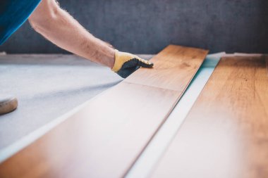 Bir işçi işini bitirirken kat kaplaması yerleştirir