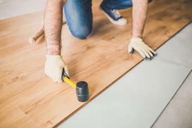 Yetişkin adam bu teknolojiyle alt tabakanın üzerine kaplama paneli yerleştiriyor.