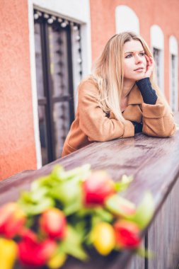 İskandinav görünümlü doğal sarışın - Zarif ceketli Danimarkalı hüzünlü ve bir buket çiçeğin yanında rüya görüyor