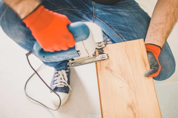 Avrupalı adam evde çalışıyor - döşeme teknolojisi - duvarın yakınındaki kaplamaları kesiyor