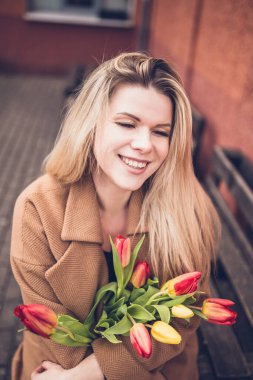 Güzel ve çekici bir kızın yüzündeki ışıltılı duygular - neşeli bir ruh hali - bir buket lale - bir erkekten hediye - sevgi ve şefkat