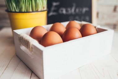 Beyaz ahşap bir masanın üzerinde çiğ tavuk yumurtası kutusunun yakın plan fotoğrafı.