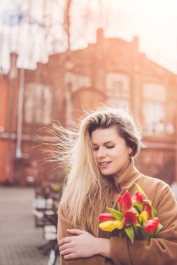 Güzel, çekici bir kızın yüzündeki parlak duygular - neşeli bir ruh hali - bir buket lale - bir adamdan hediye - gizemli bir gülümseme, neşe ve mutluluk