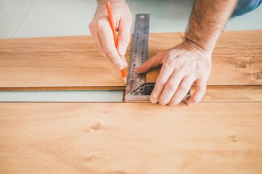 Yüzen zemin montajı - ellere yakın çekim - ev yenileme konsepti için işçi ölçümü ve işaretleme