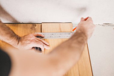 Avrupalı adam evde çalışıyor - döşeme teknolojisi - duvarın yakınındaki kaplamaları kesiyor