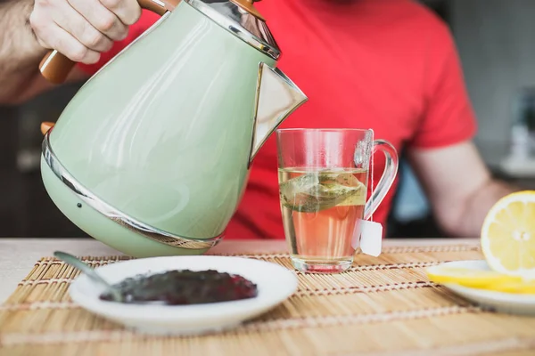 早上早餐时 人们把开水从水壶倒进杯子里 — 图库照片