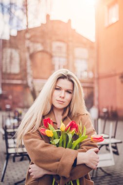 Çekici, güzel, orta yaşlı, çiçekli, uzun sarı saçlı bir kadın.