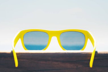 Güneşli gökyüzüne karşı güneş gözlüğü - Deniz kenarında bir yaz tatili rezervasyonu yapma zamanı