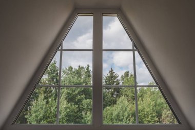 Trapezoid şekilli tavan arası penceresinin iç görünümü - pencerenin dışındaki cennet manzarası - orman ve gökyüzü
