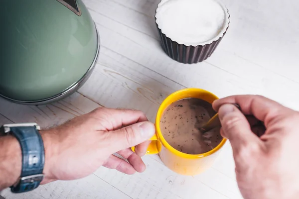 Farmer\'s rough male hands at dawn with a yellow cup of coffee - the beginning of the working day