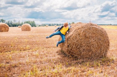 Kızıl saçlı beyaz çocuk samanlığa atlayıp dağıldı. Yazın kırsal yaşam tarzı kavramı.
