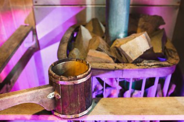 Ocağın yanındaki hamamda ahşap kepçe. Su buharı için sıcak taşlar dökülüyor.