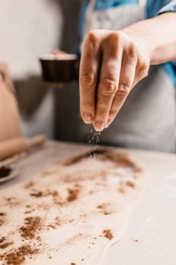 Yemek pişirirken şeker ya da tuz serpiştiren bir kadına yakın çekim odaklı.