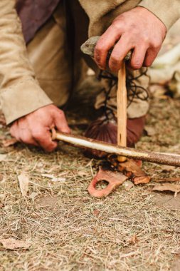 Deri kordonlu bir yay, ateşleme için yumuşak bir ahşap, vurgu ve matkap ya da serpinti için katı bir odun kullanarak nasıl ateş yakılır?