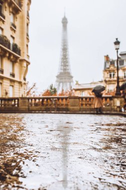 Paris 'te bir caddenin ıslak taş köprüsü yağmur sırasında sisli havada Eyfel kulesinin zeminine karşı.