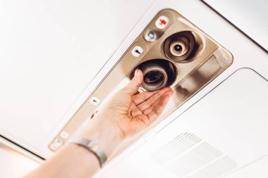 Uçaktaki bir kadın elinin yakın çekimi uçuş koltuğunun üzerine fener yerleştirir.