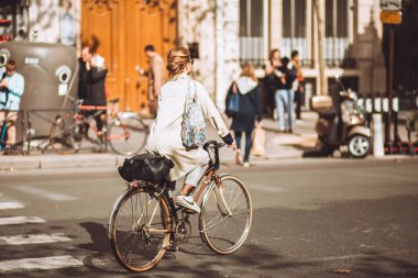 Paris, Fransa - 02 Ekim 2019: Şehirde bisiklet süren yağmurluk ve etekli genç çekici kadın