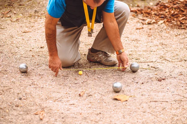 男はペタンクを果たしている ボールからターゲットボールまでの距離をチェック Coconnet — ストック写真