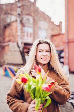 Beyaz tenli, sonbahar ceketli, güzel bir sarışın. Romantik bir buluşmadan sonra bir buket çiçekle.