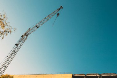 Eski harap olmuş bir binanın arka planında inşaat kulesi vinci. Şehir binalarının yeniden inşası ve yıkımı.