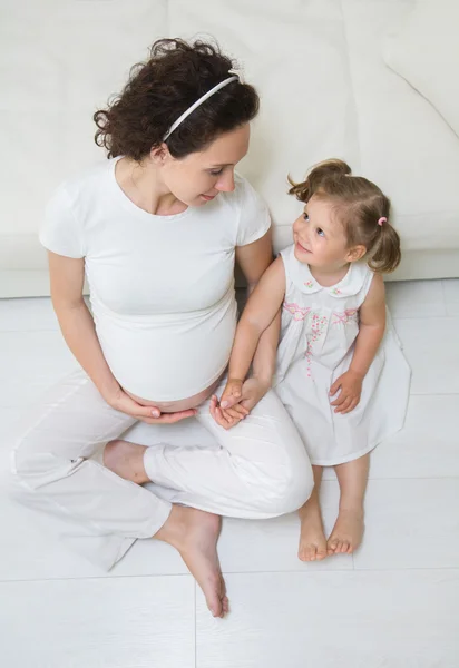 Meisje met haar zwangere moeder — Stockfoto