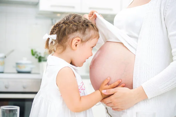 Kleines Mädchen mit ihrer schwangeren Mutter — Stockfoto