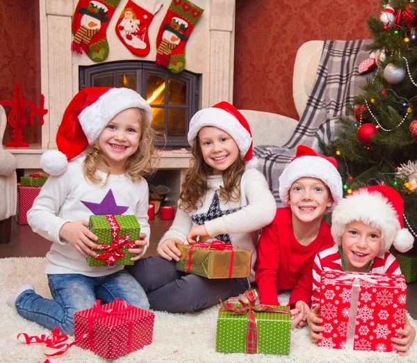 Gruppo di quattro bambini con regali alla festa di Natale — Foto Stock