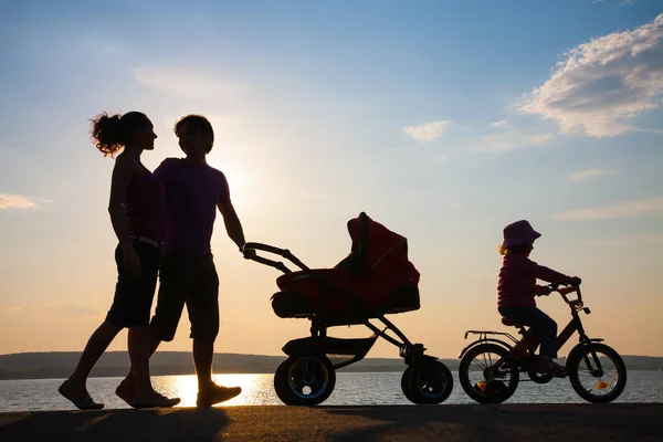 Famille heureuse marchant sur le coucher du soleil — Photo