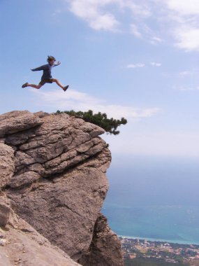 Genç adam dağlarda zıplıyor. Gökyüzü çalışıyor,