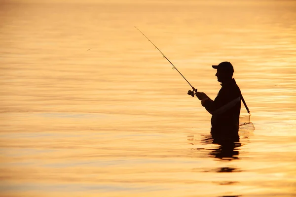Nierozpoznawalna Sylwetka Człowieka Łowiącego Ryby Zachodzie Słońca — Zdjęcie stockowe