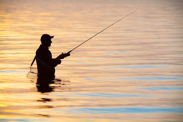 Неузнаваемый силуэт рыбалки на закате
