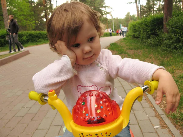 一个可爱的小女孩骑着自行车沿街走 — 图库照片